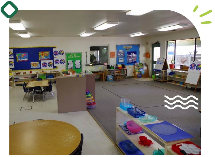 A well-organized, spacious Montessori school in visalia classroom featuring open shelves, educational materials, learning stations, and ample natural light, designed to foster student independence.